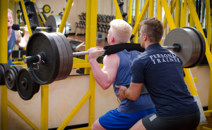 Personal trainer helping client in gym