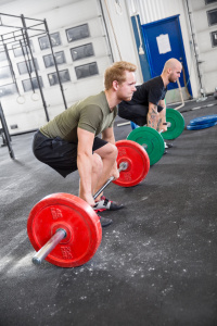 Two men train deadlift at crossfit center