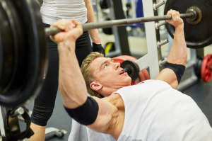 Athlete man does bench press exercise in gym hall